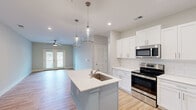 Located at 111 Teal Cir in Little River, SC, this well-appointed 2-bedroom, 2-bathroom single-story home offers a thoughtfully designed layout with modern finishes throughout. The open-concept kitchen and living area serves as the heart of the home, featuring a central island with a quartz countertop and an undermount sink, pendant lighting, white shaker cabinetry, a subway tile backsplash, and a full suite of stainless steel appliances. The living room extends naturally from the kitchen, showcasing light hardwood-style flooring and French doors that invite natural light and provide outdoor access. The primary bedroom offers plush carpeting, a ceiling fan, and its own private bathroom complete with a dual-sink vanity topped with quartz counters, stylish globe lighting, and a walk-in shower. The second bedroom also features carpet flooring and a ceiling fan, offering a comfortable and versatile space. The secondary bathroom includes a walk-in shower, a single vanity, and clean, neutral finishes. A dedicated closet provides additional storage. Soft, neutral tones and consistent modern hardware tie the home together, creating a cohesive and move-in-ready atmosphere ideal for those seeking comfortable living in coastal South Carolina.