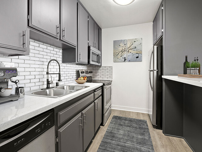 White tiled kitchen with stainless steel fridge, microwave, and oven. - Chandler Circle