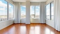 Located at 188 Clark Blvd in Brampton, Ontario, this 2-bedroom, 1-bathroom unit offers a well-designed layout across a single floor. Rich hardwood flooring runs throughout the space, complementing the clean, neutral-toned walls and creating a warm, cohesive aesthetic.

The open-concept kitchen and living area serves as the heart of the unit. The kitchen is equipped with stainless steel appliances, including a refrigerator and electric range, set against a grey tile backsplash. Dark espresso cabinetry with sleek hardware pairs with light countertops, and a peninsula provides additional workspace. The living area flows naturally from the kitchen, bathed in natural light from large floor-to-ceiling windows dressed with sheer white curtains.

Both bedrooms feature the same warm hardwood flooring and generous windows that frame elevated views of the surrounding Brampton cityscape. The primary bedroom is a comfortable size and benefits from abundant natural light. One bedroom includes a built-in sliding door closet for practical storage.

The bathroom is finished with grey tile in the walk-in shower, a wood-toned vanity with an integrated sink, and a large mirror. The hallway connects all rooms efficiently, completing this functional and modern residential unit.