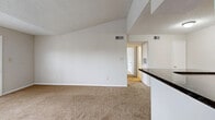 Located at 5575 Rosebriar Way in Orlando, Florida, this single-story, 3-bedroom, 1-bathroom home offers a functional and well-organized layout across its single floor. The living room is a standout space, featuring vaulted ceilings with angular lines that create a sense of openness beyond the unit's compact footprint. Neutral-toned carpet flows throughout, complemented by a textured ceiling and clean white walls. A partial wall with a dark granite countertop visually separates the living area from the kitchen.

The kitchen is fully equipped with light wood cabinetry, dark granite countertops, black appliances including a refrigerator, range, and dishwasher, and light tile flooring. A closet within the kitchen provides additional storage. Track lighting illuminates the space efficiently.

Each of the three bedrooms features carpet flooring, a ceiling fan, and windows fitted with blinds that bring in natural light. The primary bedroom includes direct outdoor access via a glass door. The shared bathroom features dual undermount sinks set in dark granite countertops atop warm wood vanity cabinetry, with tile flooring. A hallway connects the bedrooms to the main living areas, with two closets providing additional storage throughout the home.