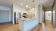 This single-floor residence at 6386 Transit Rd in Depew, NY offers a clean, contemporary design with a cohesive neutral palette and quality finishes throughout. The open-concept kitchen serves as a central highlight, featuring white shaker cabinetry, a subway tile backsplash, stainless steel appliances including a refrigerator, microwave, and range, and a large island with a granite countertop and undermount sink. Pendant lighting overhead adds a modern touch, while light-toned hardwood flooring flows through the kitchen and into the adjoining living areas. The spacious living room is bright and airy, benefiting from a ceiling fan, recessed lighting, and a large sliding glass door that draws in natural light. Bedrooms are finished with plush wall-to-wall carpeting, neutral walls, and windows that provide natural light and outside views. The primary bedroom includes a generous walk-in closet with wire shelving. The primary bathroom offers a granite-topped vanity with white cabinetry, a glass-enclosed standing shower, and hardwood-style flooring. A second full bathroom mirrors the same refined finishes, including a granite vanity and natural light from a window. The overall ambiance is bright, clean, and move-in ready.