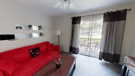 Located at Bristol Lakes in Mount Dora, Florida, this single-story residence offers a well-organized layout that makes efficient use of its space. The living room serves as the central gathering area, finished with plush carpeting, a ceiling fan, and a sliding glass door framed by bold dark curtains that opens to a private outdoor patio — ideal for enjoying the lush Florida surroundings. The galley-style kitchen is fully equipped with white cabinetry, a coil-burner electric range, refrigerator, dishwasher, and generous countertop workspace, all set atop durable tile flooring. Adjacent to the kitchen, the dedicated dining area accommodates a round glass-top table with seating for four, creating a defined space for meals. The bedroom is comfortably sized, featuring soft carpet, a ceiling fan, a large window with natural light, and ample room for full bedroom furnishings. The full bathroom includes a single-sink vanity with storage, a combined tub and shower, and tile flooring throughout. Neutral wall tones and consistent tile flooring in the common areas create a cohesive and clean aesthetic throughout the home.