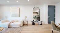 Located in Studio City, Los Angeles, this thoughtfully designed 2-bedroom, 2-bathroom residence offers a seamless single-floor layout that maximizes both function and style. Light wood flooring flows throughout, anchoring a cohesive, contemporary aesthetic defined by clean white walls and recessed lighting.

The open-concept living, dining, and kitchen area forms the heart of the home. The kitchen features flat-panel white cabinetry, warm wood upper cabinets, a subway tile backsplash, stainless steel appliances, and a central island. Stylish pendant lighting connects the kitchen to the adjacent dining area, where a modern entry door and curated wall art add character. The living room opens directly to the outdoors via expansive sliding glass doors, flooding the space with natural light and providing views of lush greenery.

The generously sized primary bedroom features dual floor-to-ceiling glass doors leading to a private balcony with open outdoor views. The second bedroom is well-proportioned, includes a closet, and maintains the same light, airy palette. Both bathrooms are finished with large-format tile flooring, sleek vanities, and tub-shower combinations with frameless sliding glass enclosures. The unit also includes in-unit laundry, two closets, and a dedicated hallway.
