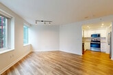 Located in the heart of Seattle at 1900 5th Ave, this one-bedroom, one-bathroom unit offers a well-designed layout that maximizes every square foot of its comfortable footprint. Warm hardwood-style flooring flows throughout, complementing the bright, neutral palette of white walls and clean trim work.

The open-concept living, dining, and kitchen area serves as the heart of the home. Oversized windows flood the living space with natural light and frame striking views of Seattle's downtown skyline. Track lighting adds a modern touch overhead. The kitchen is thoughtfully appointed with white shaker cabinetry, granite-style countertops, a classic subway tile backsplash, and a full suite of stainless steel appliances including a refrigerator, range, and built-in microwave.

The bedroom is a comfortable retreat, featuring large windows with sweeping city views and continued hardwood-style flooring. The unit includes four closets, providing exceptional storage throughout.

The bathroom offers a clean, classic finish with large-format tile flooring, a tiled tub/shower surround, a white vanity with stone countertop, and recessed lighting. A welcoming entrance hall leads seamlessly into the main living areas, completing this well-appointed urban residence.