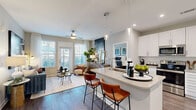 Located at 4600 Bakers Blessing Ln in Summerville, SC, this thoughtfully designed 2-bedroom, 2-bathroom residence delivers a seamless open-concept layout on a single floor. The kitchen is a standout feature, showcasing crisp white shaker cabinetry, quartz countertops, a large center island with bar seating and pendant lighting, a subway tile backsplash, and stainless steel appliances. Wood-look flooring flows throughout the main living areas, connecting the kitchen to a bright, welcoming living room filled with natural light from large windows and a glass door leading to an outdoor space. A ceiling fan adds comfort to the living area. The generously sized primary bedroom features plush carpeting, a ceiling fan, large windows, and access to a private en-suite bathroom complete with a walk-in glass shower, dual-sink vanity, and wood-look flooring. The second bedroom is equally comfortable, also featuring carpet and ample natural light. The second bathroom offers a tub-shower combination and a white vanity with quartz countertops. A hallway and closet round out this well-organized floor plan, making this Summerville residence a polished and functional living space.