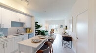 This well-designed single-floor residence offers a seamless open-concept layout that integrates the kitchen, dining, and living areas into one cohesive, light-filled space. The kitchen is outfitted with white flat-front cabinetry, stainless steel appliances including a refrigerator, range, microwave, and dishwasher, complemented by a grey tile backsplash and a light-toned breakfast bar that comfortably seats multiple guests. Large-format light tile flooring runs throughout the main living area, enhancing the bright, airy feel. The living room features a sliding glass door that opens to a private balcony, allowing natural light to flood the space and offering outdoor views. A dedicated dining area provides additional functionality within the open layout. The two bedrooms are carpeted for comfort and feature ceiling fans, generous closet space, and windows that bring in ample natural light, with views of lush palm trees visible from one bedroom. The bathroom is clean and modern, featuring a single-sink vanity with light wood cabinetry, large-format tile flooring, and a glass-enclosed walk-in shower. Throughout the residence, crisp white walls and contemporary finishes create a cohesive, inviting atmosphere well-suited to modern living.