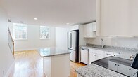 Located at 34 St Joseph St in Fall River, MA, this two-bedroom, one-bathroom residence is spread across two floors, offering a well-organized and functional layout. The main floor features an open-concept kitchen and living area anchored by warm hardwood flooring and filled with natural light from well-placed windows. The kitchen is a standout, outfitted with crisp white shaker cabinetry, granite countertops, stainless steel appliances — including a refrigerator, dishwasher, and range — and a central island that provides additional prep and dining space. The living area flows seamlessly from the kitchen, creating an inviting, connected atmosphere. Upstairs, the generously sized primary bedroom impresses with its expansive footprint, dual windows that invite abundant natural light, and the same rich hardwood flooring found throughout. The second bedroom is carpeted, features its own windows, and includes a wall-mounted mini-split system for independent climate control. The full bathroom is cleanly finished with a white vanity, tile flooring, and a tub-shower combination enclosed by sliding glass doors. Two closets provide practical storage throughout the home, and a hallway connects the spaces across both levels with ease.