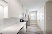 This two-story home in Valdosta, Georgia offers a well-designed layout across two floors, combining modern finishes with practical living spaces. The main level features a welcoming entrance hallway with built-in wall hooks, wood-look LVP flooring, and a staircase with warm wood-toned treads. The open-concept dining and living area is bright and airy, with a ceiling fan and a glass door leading directly to an outdoor patio. The kitchen is outfitted with white shaker cabinets, quartz countertops, a subway tile backsplash, stainless steel appliances, and a undermount sink with a matte black faucet. A convenient laundry area is integrated into the kitchen space. Both bathrooms are tastefully finished, with one featuring marble-look tile surround on the tub/shower combo and light tile flooring. The two bedrooms are located upstairs, each with neutral-toned walls, LVP flooring, ceiling fans, and ample closet space. The primary bedroom is generously sized with natural light from a window. Throughout the home, consistent neutral tones, clean white trim, and modern hardware create a cohesive and move-in-ready aesthetic.