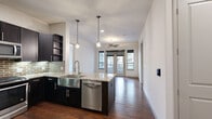 Located at 4139 Bellaire Blvd in Southside Place, TX, this single-floor 2-bedroom, 2-bathroom residence offers a thoughtfully designed open-concept layout with contemporary finishes throughout. The kitchen is a standout feature, showcasing dark espresso cabinetry, granite countertops, a brick tile backsplash, stainless steel appliances including a gas range, built-in microwave, refrigerator, and dishwasher, and a central island with a farmhouse-style sink and pendant lighting. Rich hardwood flooring extends through the kitchen and living area, which benefits from natural light and outdoor access through glass French doors and a ceiling fan. The primary bedroom is generously sized, carpeted for comfort, and features a ceiling fan, large window, and access to a well-organized walk-in closet with built-in shelving and dual hanging rods. The second bedroom is also carpeted with natural light. Both bathrooms are finished with granite vanity tops, dark cabinetry, tile flooring, and tiled tub-shower combinations. The overall ambiance is modern and clean, combining warm wood tones with neutral palettes for a polished, move-in-ready feel.