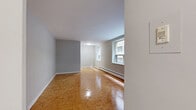 Located at 437 Jarvis St, Unit 306 in Toronto's vibrant Church-Wellesley neighbourhood, this two-bedroom, one-bathroom unit offers a practical and comfortable layout across a single floor. Throughout the unit, warm-toned parquet flooring adds a classic character and continuity between spaces.

The primary bedroom is generously proportioned — the largest of the two — and features a built-in closet, a window that lets in natural light with views of the surrounding urban streetscape, and a baseboard heating unit. The second bedroom is more compact, with its own window and the same parquet flooring, making it well-suited as a guest room or home office.

The open living area benefits from a large multi-pane window that frames city views and floods the space with natural light, enhancing the sense of openness. Neutral grey walls and white trim provide a clean, understated backdrop throughout.

The kitchen area is functional, equipped with an electric range and upper cabinetry for storage. The bathroom features a full soaking tub with white tile surround and a window for ventilation. A dedicated laundry area and a connecting hallway complete the unit's layout, adding convenience and ease of circulation throughout the home.