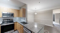Located at 4407 Hopson Rd in Durham, NC, this well-appointed single-story home offers three bedrooms, two bathrooms, and a thoughtfully designed layout across a comfortable footprint. The open-concept living and dining area is a standout, featuring dark hardwood-style flooring, crown molding, a ceiling fan, and French doors that invite natural light and outdoor views. The kitchen is well-equipped with warm honey-toned cabinetry, granite countertops, a subway tile backsplash, a center island with a dual-basin sink, and stainless steel appliances including a range, microwave, and dishwasher — all flowing seamlessly into the dining space beneath a pendant light fixture. The bedrooms are carpeted and bright, each featuring ceiling fans and windows with outdoor views. The primary bedroom offers generous proportions with ample closet space. Both bathrooms are finished with granite-topped vanities and tile surrounds, with the second bath featuring a full tub-shower combo and wood-look flooring. A dedicated laundry room houses a full-size washer and dryer. Hallways are wide and functional, with built-in HVAC vents, and a pantry and utility room add practical storage throughout. The neutral color palette and consistent finishes give the home a clean, cohesive feel.