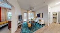 Located at 1251 Ray Charles Blvd in Tampa, Florida, this single-floor residence offers a well-designed layout with contemporary finishes throughout. The open-concept kitchen is a standout feature, equipped with stainless steel appliances, sleek grey cabinetry with under-cabinet lighting, white quartz countertops, and a generously sized island with pendant lighting — ideal for both cooking and casual dining. Light wood-style flooring flows seamlessly through the main living areas. The living room is bright and welcoming, with large windows and a glass-panel door that invite abundant natural light. A ceiling fan adds comfort, while the open layout provides a relaxed yet functional atmosphere. The bedroom makes a bold design statement with a rich terracotta accent wall, plush carpeting, large windows with views of lush greenery, and ample space for a full bedroom suite including a dedicated workspace. The bathroom continues the refined aesthetic with a double-sink vanity, grey cabinetry, wood-style flooring, a large mirror, and a full soaking tub with tile surround. A walk-in closet is accessible directly from the bathroom, adding practical storage. This residence combines modern design with everyday functionality in the heart of Tampa.