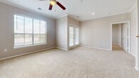 This single-story, 2-bedroom, 2-bathroom home offers a thoughtfully designed layout that makes efficient use of its space. The living area is bright and welcoming, featuring plush neutral-toned carpeting, crown molding, recessed lighting, and a ceiling fan. Large windows with slatted blinds and glass-paned French doors invite abundant natural light, creating an open and airy atmosphere.

The kitchen is equipped with rich dark wood cabinetry, tile backsplash accents, light countertops, and a full suite of black appliances, including a refrigerator, electric range with over-the-range microwave, and dishwasher. Wood-look luxury vinyl flooring runs throughout the kitchen, providing a durable and attractive finish.

The primary bedroom offers a generous footprint with soft carpeting, a ceiling fan, and natural light from a window. It is accompanied by a dedicated closet featuring elegant double panel doors. The secondary bedroom is equally comfortable with carpet flooring, a ceiling fan, and a window.

Both bathrooms are finished with wood-look flooring and neutral wall tones. The first bathroom includes a soaking tub with tiled surround featuring decorative accents, a dark wood vanity, and a toilet. The second bathroom features a glass-enclosed corner shower with matching tile detailing. A carpeted hallway connects the bedrooms and bathrooms, completing this cohesive and functional home.