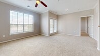 This single-story, 2-bedroom, 2-bathroom home offers a thoughtfully designed layout that makes efficient use of its space. The living area is bright and welcoming, featuring plush neutral-toned carpeting, crown molding, recessed lighting, and a ceiling fan. Large windows with slatted blinds and glass-paned French doors invite abundant natural light, creating an open and airy atmosphere.

The kitchen is equipped with rich dark wood cabinetry, tile backsplash accents, light countertops, and a full suite of black appliances, including a refrigerator, electric range with over-the-range microwave, and dishwasher. Wood-look luxury vinyl flooring runs throughout the kitchen, providing a durable and attractive finish.

The primary bedroom offers a generous footprint with soft carpeting, a ceiling fan, and natural light from a window. It is accompanied by a dedicated closet featuring elegant double panel doors. The secondary bedroom is equally comfortable with carpet flooring, a ceiling fan, and a window.

Both bathrooms are finished with wood-look flooring and neutral wall tones. The first bathroom includes a soaking tub with tiled surround featuring decorative accents, a dark wood vanity, and a toilet. The second bathroom features a glass-enclosed corner shower with matching tile detailing. A carpeted hallway connects the bedrooms and bathrooms, completing this cohesive and functional home.