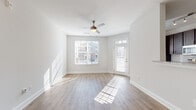Located at 12509 Crown Park Ct in Charlotte, NC, this single-floor residence offers a clean, modern aesthetic throughout. The open living and dining area greets you with warm wood-look luxury vinyl plank flooring, abundant natural light streaming through large windows with slatted blinds, and a ceiling fan overhead. A private entry door leads directly into this bright, airy space, which flows seamlessly toward the kitchen and dining area.

The kitchen is well-equipped with rich dark wood cabinetry, granite countertops, a classic white subway tile backsplash, and a full suite of stainless steel appliances, including a refrigerator, range, and over-the-range microwave. A breakfast bar provides casual seating and connects the kitchen to the main living space, which is further accented by a pendant light fixture.

The bedrooms feature soft, neutral carpeting, ceiling fans, and generously sized windows that invite natural light and views of the surrounding community. Each room provides a comfortable, restful atmosphere with ample wall space.

The bathroom is finished with granite countertops, a dark wood vanity, wood-look flooring, and a full tub-shower combo with subway tile surround and a large mirror. Throughout the residence, a consistent palette of neutral whites and warm wood tones creates a cohesive and inviting environment.