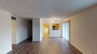 This single-floor residence offers a functional and comfortable layout designed for everyday living. The open living and dining area is finished with rich, dark wood-look laminate flooring and features a ceiling fan, a textured ceiling, and a sliding glass door that fills the space with natural light. A pass-through opening connects the living area directly to the kitchen, creating a seamless and sociable flow between spaces.

The kitchen is well-equipped with warm honey-toned wood cabinetry, dark granite-style countertops, recessed lighting, and a full suite of appliances including a white electric range, built-in microwave, dishwasher, and a top-freezer refrigerator. A window above the sink brings in additional natural light.

A bright hallway connects the main living areas to the private spaces. The bedrooms feature plush neutral carpeting, windows for natural light, and closet storage. One room features wood-look flooring and additional natural light from a window at the end of the hall.

Two bathrooms serve the residence: one with a tiled shower/tub combo, wood-look flooring, dark countertops, and vanity cabinetry, and a second more compact bathroom with a walk-in shower and wood-look flooring. Throughout, the home maintains a clean, neutral palette with white walls and consistent trim details.