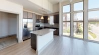 Located at 109 Knox Abbott Dr in Cayce, South Carolina, this single-floor residence showcases a contemporary design with notable architectural details throughout. The open-concept living area is defined by soaring ceilings and dramatic floor-to-ceiling windows that flood the space with natural light while offering views of the surrounding neighborhood. French doors provide additional access to the outdoors, and built-in shelving adds functional display space to the living area. Light wood-tone flooring runs throughout the main living spaces, contributing to the bright, modern aesthetic.

The kitchen is a standout feature, equipped with dark espresso cabinetry, a subway tile backsplash, granite countertops, a large center island with pendant lighting, and a full suite of stainless steel appliances. A dedicated laundry area with a full-size washer provides added convenience.

The bedrooms feature plush carpeting, ceiling fans, and windows with blinds for natural light and privacy. Both bathrooms are finished consistently, each offering tile flooring, a soaking tub with tiled surround, granite-topped dark vanities, and brushed nickel fixtures, creating a cohesive and polished feel throughout.