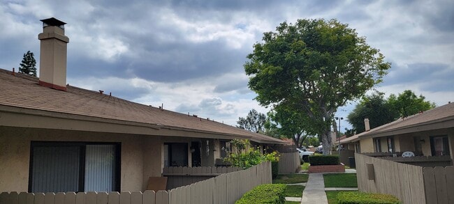 Árboles maduros y jardines a lo largo de los pasillos de Las Casitas Apartments en Riverside, California. - Las Casitas Apartments