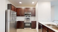 Located at 2100 Memorial Drive in Houston's desirable 77007 corridor, this two-bedroom, one-bathroom residence offers a well-designed single-level floor plan with thoughtful finishes throughout. The kitchen is a standout feature, showcasing rich dark-wood cabinetry, marble-style countertops, a classic subway tile backsplash, and a full suite of stainless steel appliances including a refrigerator, range, over-the-range microwave, and dishwasher. A peninsula with an integrated sink and additional counter space extends the kitchen into the living area, creating an open and connected layout ideal for everyday living and entertaining. Light wood-tone flooring runs throughout the main living spaces, complementing the bright, neutral color palette. The spacious primary bedroom features a ceiling fan, natural light from a multi-pane window, and wood flooring, while the second bedroom offers plush carpeting, a ceiling fan, and its own window view. The full bathroom is well-appointed with dark-wood vanity cabinetry, marble-style countertops, a large mirror, tiled shower, and accessibility grab bars. A dedicated closet and hallway complete the layout, providing practical storage and circulation throughout this comfortable Houston residence.
