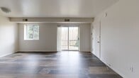 Located at 385 Harrison Ave in Upper Darby, PA, this one-bedroom, one-bathroom unit offers a thoughtfully laid-out single-floor plan. Rich, multi-toned hardwood-style flooring runs throughout, lending warmth and continuity to every room.

The combined living and dining area is the heart of the home, bathed in natural light from a large window and a sliding glass door that opens onto a private balcony with views of surrounding greenery. The open feel of this space makes it ideal for both relaxing and entertaining.

The galley-style kitchen is efficiently designed with slate-blue cabinetry lining both sides, white countertops, and white appliances, including an electric range and refrigerator. A dedicated pantry provides additional storage just off the kitchen.

The spacious bedroom features a wide window framing tree-lined outdoor views, two closets offering generous storage, and the same warm flooring found throughout the unit. The bathroom includes a full bathtub and shower combination.

Additional practical spaces include a hallway, a utility room, and two closets distributed across the unit. Clean white walls and consistent finishes throughout create a cohesive, move-in-ready aesthetic. The private balcony adds a desirable outdoor retreat to this well-appointed Upper Darby residence.
