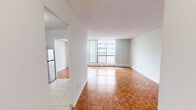 Located on the 22nd floor at 555 Sherbourne Street in Toronto's St. James Town neighbourhood, this 2-bedroom, 1-bathroom unit offers a practical and well-organized single-level layout. Warm-toned parquet flooring runs throughout the living areas and bedrooms, adding a classic character to the space.

The spacious living room is a standout feature, anchored by a large floor-to-ceiling window wall with sliding balcony access, flooding the room with natural light and offering open views of the Toronto skyline. The private balcony extends the living space outdoors, providing an elevated urban vantage point.

The kitchen is functionally laid out with white cabinetry, a stainless steel refrigerator, and light tile flooring, connected through an open archway to the living area. The primary bedroom is generously sized, featuring its own window with city views and parquet flooring, while the second bedroom offers similar finishes and natural light. Both bedrooms are well-proportioned and versatile.

The bathroom is clean and straightforward, featuring a full-sized soaker tub and shower combination with white tile surround. Two hallways connect the rooms efficiently. The unit's elevated position provides sweeping views of the surrounding cityscape throughout.