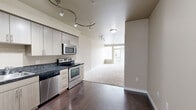 Located in Seattle's 98122 zip code, this Terravita one-bedroom, one-bathroom residence offers a thoughtfully organized single-floor layout. The kitchen is a standout feature, equipped with stainless steel appliances including a refrigerator, electric range, microwave, and dishwasher. Light wood cabinetry extends to the ceiling, providing ample storage, while dark granite countertops add a sleek, modern contrast. Rich dark hardwood flooring runs throughout the kitchen and entry areas, anchoring the space with warmth and style. The open layout transitions seamlessly into the living area, which features plush neutral carpeting and a large window that invites generous natural light and views of the surrounding neighborhood. The bedroom is a comfortable retreat, also carpeted, with a sizable closet featuring built-in shelving and hanging rods for organized storage. The full bathroom includes a tub/shower combination with tile surround, tile flooring, and a vanity with countertop storage. Track lighting throughout adds a contemporary touch, providing flexible and functional illumination across the living spaces. This residence offers a clean, modern aesthetic well-suited for comfortable urban living in Seattle.
