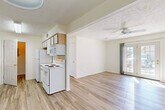 Located at 1400 Gallery Place Dr in Jackson, Michigan, this single-floor, 2-bedroom, 2-bathroom residence offers a practical and comfortable layout. The open-concept kitchen and living area form the heart of the home, featuring light wood-style flooring throughout. The kitchen is equipped with white appliances, including a range with coil burners, a built-in microwave, and a refrigerator, complemented by light wood cabinetry and a single-basin sink. The adjacent living area is bright and airy, highlighted by a ceiling fan and a set of french doors that invite natural light and provide outdoor access. Both bedrooms are carpeted and receive ample natural light through large windows. The spacious primary bedroom includes a dedicated closet with wire shelving for organized storage. The two bathrooms are well-appointed: one features a full tub-shower combination with hardwood-style flooring, while the second offers a glass-enclosed walk-in shower. A dedicated utility room adds everyday convenience. Throughout the residence, textured ceilings, neutral walls, and clean finishes contribute to a bright, move-in-ready ambiance.