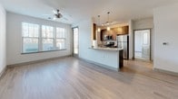 Located at 100 Whitworth Way in Williamsburg, Virginia, this single-floor residence offers a thoughtfully designed open-concept layout with a clean, contemporary aesthetic throughout. The living and dining area is highlighted by light wood-style flooring, a ceiling fan, and generous natural light streaming through large windows dressed with horizontal blinds, creating a bright and welcoming atmosphere. Sliding door access adds further connectivity to the living space.

The kitchen is a standout feature, showcasing dark wood cabinetry, granite countertops, a central island with a built-in sink, pendant lighting, and a full suite of stainless steel appliances including a refrigerator, range, and microwave. A convenient in-unit stacked washer and dryer is also present.

The bedrooms offer plush wall-to-wall carpeting, ceiling fans, and ample natural light. One bedroom includes a spacious walk-in closet, while the other features a double window with views to the exterior. The bathroom is well-finished with dark wood vanity cabinetry, granite countertops, a large framed mirror, and a tub-shower combination with tile surround. Light wood-style flooring extends throughout the bathroom, complementing the cohesive design of the home.