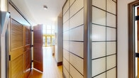 This two-story space showcases a contemporary loft design that blends industrial and modern elements throughout. The main level is anchored by warm hardwood flooring that extends through the open-concept living area and into the kitchen. A bold steel-and-wood open staircase with wire mesh railings serves as a central architectural feature, ascending to the upper mezzanine level while allowing sightlines to flow freely across both floors. Large floor-to-ceiling windows and sliding glass doors flood the main living area with abundant natural light, offering views to an outdoor balcony.

The kitchen is well-appointed with light maple cabinetry, dark granite countertops, a glass tile backsplash, stainless steel appliances, and a built-in dishwasher. The entry corridor features a distinctive wall of paneled storage units with a clean grid design, adding a refined, architectural quality to the arrival experience.

Two bathrooms are present, both finished with stone-tile flooring and dark granite countertops with vessel sinks. One includes a glass-enclosed walk-in shower. The upper mezzanine level is carpeted and open to the floor below via the metal railing system, with exposed ductwork lending an industrial character and windows providing continued natural light.