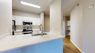 Located at 1456 E Pecos Rd in Gilbert, AZ, this well-appointed one-bedroom, one-bathroom unit offers a thoughtfully designed single-floor layout. The open-concept kitchen is a standout feature, showcasing white shaker cabinetry, a large peninsula with a white quartz countertop and an undermount sink with a modern gooseneck faucet, and a full suite of stainless steel appliances including a refrigerator, electric range, microwave, and dishwasher. A skylight above the kitchen fills the space with natural light. Wood-style flooring runs throughout the entire unit, lending a warm and cohesive aesthetic. The living room is bright and airy, featuring a sliding glass door that opens to a private patio with outdoor views of surrounding greenery. The generously sized bedroom includes a ceiling fan, a large window for natural light, and direct access to both a walk-in closet and the hallway. The bathroom features a single-sink vanity with white countertops, a mirror, and a full shower-tub combination. Neutral-toned walls throughout create a clean, modern backdrop, while the efficient layout maximizes every inch of the comfortable living space.