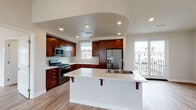 Located at 1075 Portside Dr in Ventura, California, this well-designed two-floor residence offers a thoughtfully laid-out interior finished with consistent hardwood-style flooring and a clean, contemporary aesthetic throughout. The open-concept kitchen serves as a central highlight, featuring rich dark-wood cabinetry, light quartz countertops, stainless steel appliances including a gas range and French door refrigerator, and a generous center island with a built-in sink and breakfast bar seating. Recessed lighting and an architectural arched ceiling detail add character to the kitchen and adjoining living area. Large sliding glass doors lead to a private balcony, inviting natural light and outdoor views of the Ventura surroundings. The living space is open and airy, enhanced by recessed lighting and neutral wall tones. Bedrooms are spacious with elevated ceilings, ample natural light from windows, and direct access to walk-in closets with built-in shelving. Bathrooms are finished with rich wood vanities, light quartz surfaces, brushed nickel fixtures, and tiled tub-shower combinations. A dedicated walk-in closet provides generous storage. The overall ambiance is clean, modern, and move-in ready, reflecting quality finishes suited to coastal California living.