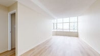 Located at 169 Lees Ave in Ottawa's Centretown neighbourhood, this one-bedroom, one-bathroom unit offers a bright and functional layout across a single floor. The open living area is a standout feature, highlighted by expansive floor-to-ceiling windows that wrap around a corner, flooding the space with natural light and framing sweeping views of the Ottawa skyline. Light-toned hardwood flooring runs throughout the main living areas and bedroom, contributing to a clean and contemporary aesthetic with neutral warm-white walls throughout.

The kitchen is distinct from the living area and features white cabinetry, granite-style countertops, a tile floor, and white appliances including an electric range — offering a practical and well-organized cooking space.

The bedroom is a comfortable, well-proportioned room with a window providing natural light and city views, a baseboard heater, and a double-door closet for ample storage. The hallway connects each room efficiently and includes ceiling-mounted smoke detectors.

The bathroom is finished in a clean, all-white palette, featuring a soaker bathtub with a shower, chrome fixtures, and tile flooring. Overall, the unit presents a bright, move-in-ready space well-suited to urban living in Ottawa.