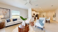 Located at 9031 Mandoline Dr in Sarasota, Florida, this two-story home showcases a clean, contemporary design characterized by bright white walls, recessed lighting, and light-toned tile flooring throughout the main living areas. The open-concept first floor creates a seamless flow between the living, dining, and kitchen spaces. The living room is generously proportioned, featuring a ceiling fan, large windows that admit abundant natural light, and views of the surrounding landscape through sliding glass doors.

The kitchen is a standout feature, equipped with white shaker-style cabinetry, light quartz countertops, stainless steel appliances, and a spacious island with bar seating — well-suited for both everyday living and entertaining. A dedicated dining area with a round wood table sits adjacent to the kitchen, completing the social hub of the home.

The upper level hosts the bedrooms, each finished with plush carpeting and large windows offering natural light and outdoor views. Bathrooms are finished in neutral tones with white vanities and clean tilework. A dedicated laundry area with full-size washer and dryer adds everyday convenience. The attached garage provides additional storage and parking, rounding out this well-appointed Sarasota home.