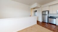 Located at 124 Shellbark Way in Savannah, Georgia, this single-floor residence offers a thoughtfully arranged layout that balances open common areas with comfortable private spaces. The kitchen is outfitted with stainless steel appliances—including a refrigerator, electric range, built-in microwave, and dishwasher—paired with dark countertops and crisp white cabinetry. Wood-style flooring runs throughout the kitchen and dining area, lending warmth and easy maintenance to the space. A half-wall partition separates the kitchen from the living area, which transitions to plush carpeting and provides a relaxed, defined gathering space. A dedicated closet nearby houses an in-unit washer and dryer, adding everyday convenience. The bedrooms feature soft carpeting, ceiling fans with lighting, and windows fitted with blinds that allow natural light while maintaining privacy, with views of the surrounding neighborhood. The bathroom is accessible through sliding doors and offers a functional layout with a vanity featuring dark countertops, white cabinetry, a medicine cabinet, and a tub-shower combination. Clean white walls and neutral finishes throughout create a bright, cohesive atmosphere well-suited to a variety of furnishing styles.