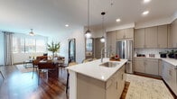 This single-floor residence showcases a thoughtfully designed open-concept layout that seamlessly connects the kitchen, dining, and living areas. The kitchen is a standout feature, equipped with stainless steel appliances, taupe flat-front cabinetry extending to the ceiling, a white quartz countertop island with an undermount sink, and globe pendant lighting that adds a modern touch. Rich hardwood-style flooring flows throughout the main living spaces, complementing the light and airy color palette.

The living room is bright and inviting, with large windows offering views of palm trees and a pool area, filling the space with natural light. A ceiling fan adds to the comfort of the room.

The bedroom is a comfortable retreat featuring plush carpeting, large windows that allow ample natural light, and generous wall space for décor. The bathrooms are well-appointed with grey cabinetry, white quartz vanity surfaces, lighted mirrors, full-size soaking tubs with shower combinations, and hardwood-style flooring — both presenting a clean, contemporary aesthetic.

Recessed lighting throughout the residence enhances the modern ambiance, while the open floor plan promotes a sense of spaciousness and functionality ideal for everyday living.