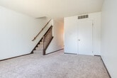 Located at 804 12th Ave S in Onalaska, Wisconsin, this two-story home offers three bedrooms, one bathroom, and a practical layout spread evenly across two floors. The main level features a combined kitchen and dining area equipped with dark wood cabinetry, granite-style laminate countertops, a double-basin sink, a white electric range, and a full-size refrigerator. Tile flooring runs throughout the kitchen, while a ceiling fan adds comfort overhead. The living room on the main level is carpeted and features a staircase with a wooden railing leading to the upper floor, along with a HVAC vent and easy access to the entry door. The upper level hosts all three bedrooms, each finished with neutral carpet, white walls, and dark wood trim. The primary bedroom is generously sized and includes a closet. The additional bedrooms are well-proportioned, with one featuring a window that brings in natural light. Notably, the home includes seven closets in total, providing exceptional storage throughout. The full bathroom features a clean white tub-shower combination with chrome fixtures. Textured ceilings are consistent throughout the home, and the overall layout is functional and well-organized.