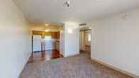 Located at 5651 E Edison St in Tucson, Arizona, this single-floor unit offers a practical and comfortable layout designed for everyday living. The open living area is finished with plush carpeting and flows seamlessly toward a sliding glass door fitted with vertical blinds, allowing natural light to fill the space while providing access to an outdoor patio with neighborhood views.

The kitchen is positioned adjacent to the living area and features warm honey-toned wood cabinetry with ample upper and lower storage, light-toned laminate countertops, a coil-burner electric range with overhead ventilation, a stainless steel sink, and a full-size refrigerator. Rich hardwood-style flooring runs throughout the kitchen, adding a welcoming contrast to the carpeted living spaces. A ceiling fan is installed above the kitchen area for added comfort.

The bedrooms are carpeted and well-proportioned, each offering large windows that bring in natural light. One bedroom includes a sliding-door closet with built-in shelving, providing functional storage. The bathroom features hardwood-style flooring, a full-size soaking tub and shower combo with distinctive wood-grain patterned wall surrounds, and clean white fixtures. A textured ceiling is consistent throughout the unit, and neutral wall tones create a bright, move-in-ready atmosphere.