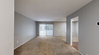 This single-story, one-bedroom, one-bathroom unit in Northville, Michigan offers a well-organized layout that makes efficient use of its available floor area. The combined kitchen and living room forms the heart of the unit, with the living area finished in neutral-toned carpet and painted in a soft gray palette throughout. A sliding glass door with vertical blinds anchors the living room, filling the space with natural light and providing direct access to a private balcony with outdoor views.

The kitchen is equipped with dark espresso-finish cabinetry offering ample upper and lower storage, light speckled countertops, hardwood-style flooring, and a white gas range with overhead ventilation. The open configuration between the kitchen and living area supports a functional, connected flow.

The bedroom is a generously proportioned room with plush carpeting, gray walls, and a standard window that admits natural light. A six-panel closet door provides access to a dedicated closet, offering practical storage. The consistent use of neutral tones and carpet throughout the bedroom and living areas creates a cohesive, understated aesthetic across the entire unit.