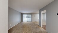 This single-story, one-bedroom, one-bathroom unit in Northville, Michigan offers a well-organized layout that makes efficient use of its available floor area. The combined kitchen and living room forms the heart of the unit, with the living area finished in neutral-toned carpet and painted in a soft gray palette throughout. A sliding glass door with vertical blinds anchors the living room, filling the space with natural light and providing direct access to a private balcony with outdoor views.

The kitchen is equipped with dark espresso-finish cabinetry offering ample upper and lower storage, light speckled countertops, hardwood-style flooring, and a white gas range with overhead ventilation. The open configuration between the kitchen and living area supports a functional, connected flow.

The bedroom is a generously proportioned room with plush carpeting, gray walls, and a standard window that admits natural light. A six-panel closet door provides access to a dedicated closet, offering practical storage. The consistent use of neutral tones and carpet throughout the bedroom and living areas creates a cohesive, understated aesthetic across the entire unit.