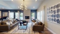 Located at 1800 Sidney Ave in Port Orchard, Washington, this single-story community clubhouse is thoughtfully designed to offer residents a refined and functional gathering space. The main lounge serves as the centerpiece of the facility, featuring a striking floor-to-ceiling stone fireplace flanked by glass doors that open to an outdoor pool area, flooding the room with natural light. Deep navy accent walls contrast beautifully with warm hardwood flooring, while a bold multi-arm chandelier adds a contemporary focal point overhead. Comfortable leather and upholstered seating arrangements invite relaxed socializing throughout the space. An adjacent flex room provides versatile seating options, including a large sectional sofa and a live-edge communal high-top table, all set against large windows that keep the space bright and airy. A bar and dining area features hardwood floors, wall-mounted TV, high-top seating islands, and additional bistro-style tables for casual dining or work. The full kitchen is outfitted with stainless steel appliances, a sleek electric range, generous counter space, white cabinetry with matte black hardware, and a dramatic textured tile backsplash that serves as a standout design element. Throughout the clubhouse, a cohesive modern aesthetic is maintained through careful attention to finishes, lighting, and thoughtful furnishings.