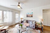 Located at 4221 E Ray Rd in Phoenix, AZ, this efficiently designed single-floor unit offers a well-organized layout comprising a combined living and dining room, a full kitchen, a bathroom, a closet, and a hallway. The living area is bright and welcoming, featuring wood-look flooring, a ceiling fan, and large windows dressed with grommet curtains that allow natural light to fill the space. Southwest-inspired artwork adorns the white walls, complementing the warm, desert-themed aesthetic throughout. The dining area is anchored by a round wooden table beneath a modern geometric pendant light, with vibrant Arizona landscape paintings adding a regional character to the space. The kitchen is well-appointed with white cabinetry, light countertops, a subway tile backsplash, and a full suite of stainless steel appliances including a refrigerator, range, microwave, and dishwasher. Wood-look flooring extends seamlessly through the kitchen, enhancing the cohesive design. The bathroom features a clean, contemporary finish with a white vanity, a large mirror, a combination tub and shower, and wood-look tile flooring. Throughout the unit, the white walls and consistent flooring create a unified, airy atmosphere that reflects the sun-filled spirit of Phoenix living.