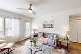 Located at 4221 E Ray Rd in Phoenix, AZ, this efficiently designed single-floor unit offers a well-organized layout comprising a combined living and dining room, a full kitchen, a bathroom, a closet, and a hallway. The living area is bright and welcoming, featuring wood-look flooring, a ceiling fan, and large windows dressed with grommet curtains that allow natural light to fill the space. Southwest-inspired artwork adorns the white walls, complementing the warm, desert-themed aesthetic throughout. The dining area is anchored by a round wooden table beneath a modern geometric pendant light, with vibrant Arizona landscape paintings adding a regional character to the space. The kitchen is well-appointed with white cabinetry, light countertops, a subway tile backsplash, and a full suite of stainless steel appliances including a refrigerator, range, microwave, and dishwasher. Wood-look flooring extends seamlessly through the kitchen, enhancing the cohesive design. The bathroom features a clean, contemporary finish with a white vanity, a large mirror, a combination tub and shower, and wood-look tile flooring. Throughout the unit, the white walls and consistent flooring create a unified, airy atmosphere that reflects the sun-filled spirit of Phoenix living.