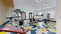 The Luxe of Southaven's amenity space is a thoughtfully designed, single-floor facility that combines fitness, socializing, and relaxation in a cohesive, modern environment. The layout connects several distinct areas, each with its own character while maintaining a unified design language of light wood flooring, dark-trimmed doors, and bold accent colors throughout.

The fitness center is a well-equipped space featuring a variety of strength and cardio machines, including cable systems, treadmills, and a rowing machine. Its most striking feature is the geometric hexagonal floor tiling in yellow, teal, and gray, which adds dynamic visual energy to the room. Natural light filters in through windows, complementing the recessed and panel ceiling lighting.

The lounge area showcases deliberate design contrast, pairing a dramatic black-and-white marble accent wall with rattan seating and warm Edison bulb lighting in one corner, while another seating nook features contemporary yellow and teal chairs alongside artistic wall-mounted sconce lighting that casts sculptural shadow patterns.

The game room offers a foosball table and a billiards table alongside a statement concrete-textured accent wall adorned with live-edge wood floating shelves, creating an industrial yet warm atmosphere. Together, these spaces deliver a versatile and visually engaging communal environment.