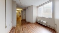 Located at 1081 Court Avenue in Memphis, Tennessee, this single-floor unit offers a efficiently arranged layout across five distinct areas. Warm wood-look flooring runs throughout the space, providing a cohesive and easy-to-maintain surface underfoot.

The kitchen is well-appointed with rich dark-wood cabinetry, light countertops, a white electric range with overhead ventilation, a stainless steel sink, and a full-size refrigerator. A small built-in work surface adds functional utility, and open sightlines connect the kitchen to the hallway beyond.

The living area features neutral walls, a wall-mounted HVAC unit, and a window fitted with horizontal blinds that allows natural light to filter in. A hallway corridor connects the main rooms, maintaining an open and navigable flow throughout the unit.

The bedroom is a calm, neutral space with wood-look flooring, a window with blinds, and a closet equipped with a wire shelving rack for organized storage. A secondary room offers additional flexible space, featuring a textured ceiling and exposed structural elements.

The bathroom is designed with accessibility in mind, featuring a full soaking tub with a fold-down shower bench, multiple grab bars, a handheld showerhead, a wall-mounted sink, and classic white tile flooring — providing both safety and comfort.