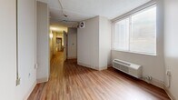 Located at 1081 Court Avenue in Memphis, Tennessee, this single-floor unit offers a efficiently arranged layout across five distinct areas. Warm wood-look flooring runs throughout the space, providing a cohesive and easy-to-maintain surface underfoot.

The kitchen is well-appointed with rich dark-wood cabinetry, light countertops, a white electric range with overhead ventilation, a stainless steel sink, and a full-size refrigerator. A small built-in work surface adds functional utility, and open sightlines connect the kitchen to the hallway beyond.

The living area features neutral walls, a wall-mounted HVAC unit, and a window fitted with horizontal blinds that allows natural light to filter in. A hallway corridor connects the main rooms, maintaining an open and navigable flow throughout the unit.

The bedroom is a calm, neutral space with wood-look flooring, a window with blinds, and a closet equipped with a wire shelving rack for organized storage. A secondary room offers additional flexible space, featuring a textured ceiling and exposed structural elements.

The bathroom is designed with accessibility in mind, featuring a full soaking tub with a fold-down shower bench, multiple grab bars, a handheld showerhead, a wall-mounted sink, and classic white tile flooring — providing both safety and comfort.