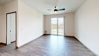 Located at 6219 Williamsburg Way in De Forest, WI, this well-appointed 2-bedroom, 2-bathroom unit offers a thoughtfully designed single-level floor plan with a clean, contemporary aesthetic throughout. The open-concept kitchen serves as the heart of the home, showcasing white shaker cabinetry with matte black hardware, white quartz countertops, a classic subway tile backsplash, stainless steel appliances, and a central island with pendant lighting — all set over warm wood-look flooring. The adjoining living area features a ceiling fan, sliding glass doors opening to a private balcony, and outdoor views of the surrounding landscape. The primary bedroom is generously sized with plush carpeting, a large window, a ceiling fan, and direct access to its own bathroom. The en-suite bath features a white vanity, wood-look flooring, and leads directly into a spacious walk-in closet with adjustable wire shelving. The second bedroom also offers carpeted flooring, natural light, and closet access. A second full bathroom includes a soaking tub, vanity, and a conveniently located in-unit washer. Both walk-in closets provide ample built-in storage. The unit combines modern finishes with functional design for comfortable everyday living.