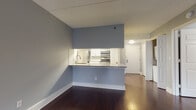 Located at 7912 River Rd in North Bergen, NJ, this single-floor residence offers a well-organized layout designed for comfortable everyday living. The open-concept living area is anchored by rich, dark hardwood flooring and soft, neutral gray walls that create a calm and cohesive atmosphere throughout the space.

The kitchen is a standout feature, designed with a pass-through counter that opens directly into the living area, promoting a connected and sociable flow. White cabinetry with sleek brushed-nickel hardware pairs with granite-style countertops and a mosaic tile backsplash. Stainless steel appliances, including a refrigerator, microwave, and range, complete the functional and modern setup.

The bedroom is generously sized, featuring plush wall-to-wall carpeting and a large window fitted with vertical blinds, allowing natural light while maintaining privacy. A wall-mounted HVAC unit ensures year-round climate comfort.

The bathroom is cleanly appointed with light tile flooring, a dark-toned vanity with a framed mirror, and well-lit overhead fixtures. A hallway with wall sconce lighting and white panel doors connects the main areas with ease, adding an elegant transitional element to the interior design. The overall aesthetic is modern, clean, and move-in ready.