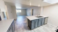 Located at 3901 Indian School Rd NE in Albuquerque, New Mexico, this single-floor, two-bedroom, two-bathroom residence offers a well-designed layout with modern finishes throughout. The open-concept kitchen and living area serves as the heart of the home, anchored by a large island with a white quartz countertop and a deep stainless steel sink. The kitchen features two-tone cabinetry in slate blue and white, stainless steel appliances including an electric range and microwave, and a skylight that fills the space with natural light. The living room is spacious and inviting, highlighted by a white-tiled fireplace, large windows, and a sliding glass door that brings in additional natural light. Tile-style luxury flooring runs throughout the main living areas, while the bedrooms are finished with plush carpeting. The primary bedroom is generously sized, offering a sliding glass door access and a dedicated closet. Both bathrooms mirror each other in design, each featuring a tub-shower combo with white tile surround, a single-sink vanity with slate blue cabinetry, and stone-look tile flooring. Two hallways and two closets add practical storage and circulation throughout this efficiently designed home.