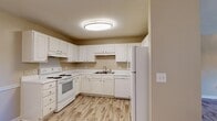 This single-story residence presents a practical and well-organized layout designed for comfortable everyday living. The interior is finished with warm, neutral tones throughout, complemented by light wood-look laminate flooring that extends across the main living areas, kitchen, and bathrooms, while plush carpeting is found in the bedroom.

The kitchen is a functional centerpiece of the home, featuring an abundance of white cabinetry that provides generous storage space. White appliances include an electric range, refrigerator, and dishwasher, all set against clean white countertops. A flush ceiling light illuminates the space efficiently. The kitchen opens toward a dining area, which is distinguished by an elegant chandelier that adds a refined touch to the otherwise understated setting. A built-in shelving closet is conveniently accessible from the dining area.

The living area is spacious and airy, equipped with a ceiling fan and a window that allows natural light to filter in. The bedroom is comfortably sized, also featuring a ceiling fan for climate control.

Two full bathrooms serve the unit, each including a tub-shower combination, toilet, and a vanity with under-cabinet storage. The overall ambiance is clean, bright, and move-in ready.