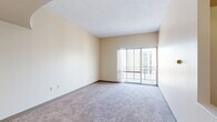 Located at 630 Wabash Avenue in Terre Haute, Indiana, this one-bedroom, one-bathroom unit offers a well-organized and functional floor plan across a single level. The combined living and dining area is generously sized, featuring neutral-toned carpeting, warm beige walls, and a textured ceiling that adds subtle character. Large sliding glass doors flood the space with natural light and open directly onto a private balcony, providing outdoor views of the surrounding cityscape. A pendant light fixture accents the dining area, adding a touch of definition to the open layout. The kitchen is efficiently arranged and conveniently accessible from the main living space. The bedroom is a comfortable size, featuring two windows that bring in ample natural light and offer urban views. It is complemented by both a walk-in closet and an additional closet, providing notable storage capacity. Elevated ceilings throughout the unit contribute to an open, airy ambiance. A full bathroom, hallway, and utility room round out the layout, ensuring practical everyday functionality. The overall design is clean, straightforward, and well-suited for comfortable single-occupant or couple living in the heart of Terre Haute.